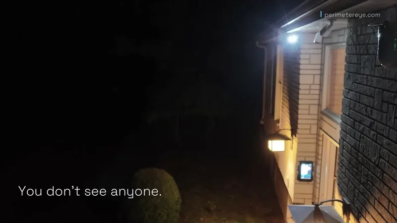 The side of the house at night beside a dark driveway, with no one visible